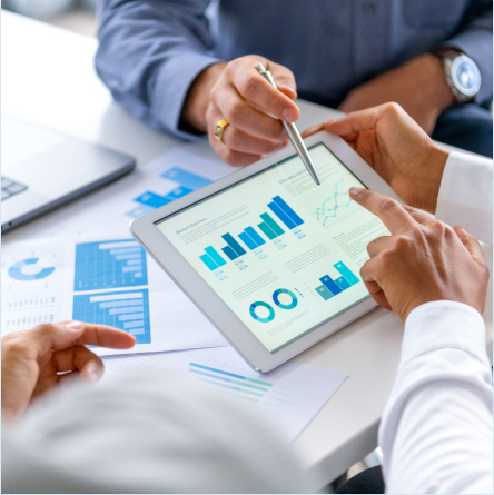 Two people discussing business analytics on a tablet showing bar charts, line graphs, and pie charts.
